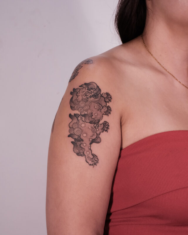 Fine line Foo Dog tattoo on the upper arm by Azone Tattoo Studio in Hanoi