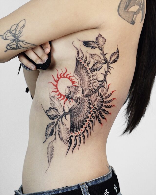 Powerful black-and-red bird tattoo rising with the sun – symbol of rebirth and freedom, Azone Tattoo Hanoi
