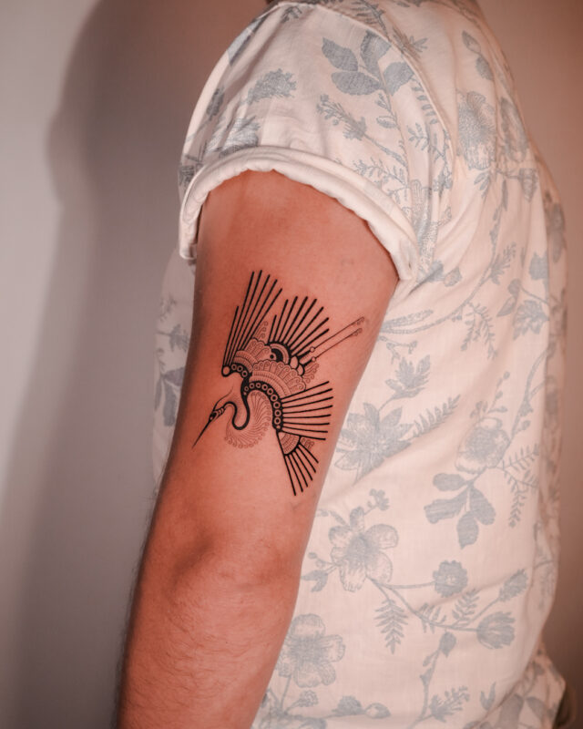 Blackwork crane tattoo on the upper arm by Azone Tattoo Studio in Hanoi and Saigon