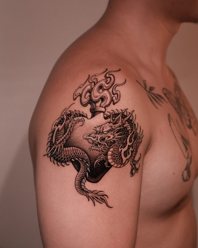 Blackwork dragon tattoo with a traditional flask on the upper arm by Azone Tattoo Studio in Hanoi and Saigon
