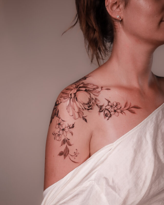 Black and grey peony floral tattoo across the shoulder by Azone Tattoo Studio in Hanoi and Saigon