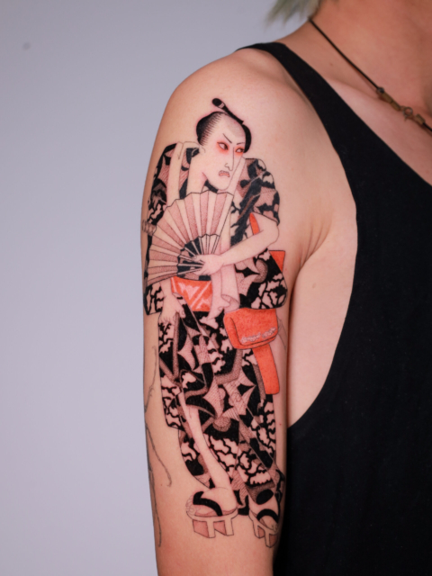 Japanese ukiyo-e inspired figure holding a folding fan tattoo on the upper arm